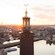 A square tower, with 3 golden crowns at its pinnacle, rises above Stockholm, Sweden